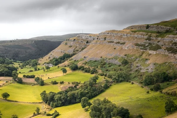 A Lush Green Valley Surrounded by Mountains Under A Cloudy Sky. Llangollen